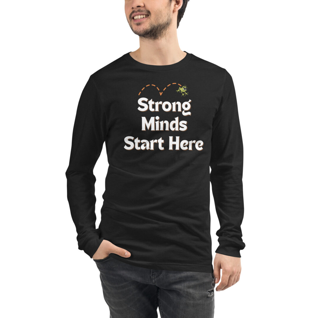 "Strong Minds Start Here" Unisex Long Sleeve Tee (Positive Leaps logo on back) 2 A person wearing a black long-sleeved shirt with the "Strong Minds Start Here" message and a small frog graphic, representing the Positive Leaps mission.
