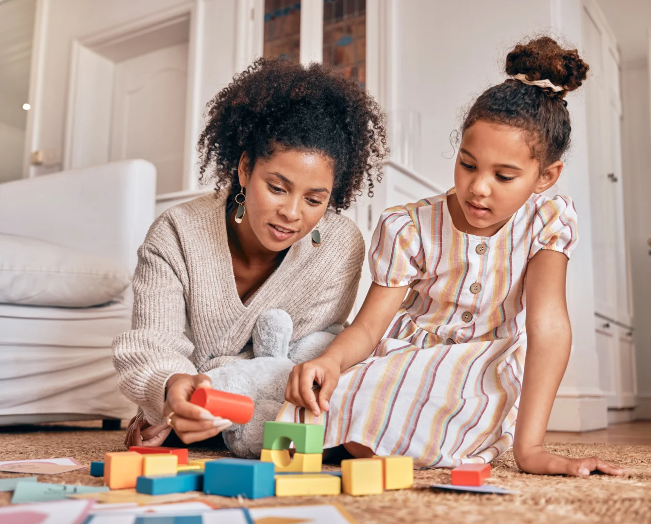 A pediatric behavioral therapist working with a young girl using colorful building blocks for developmental learning.